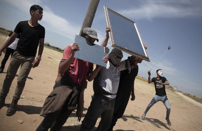 Des manifestants palestiniens tentent d’éblouir les soldats israéliens en brandissant des miroirs, lundi 2 avril, à Gaza.