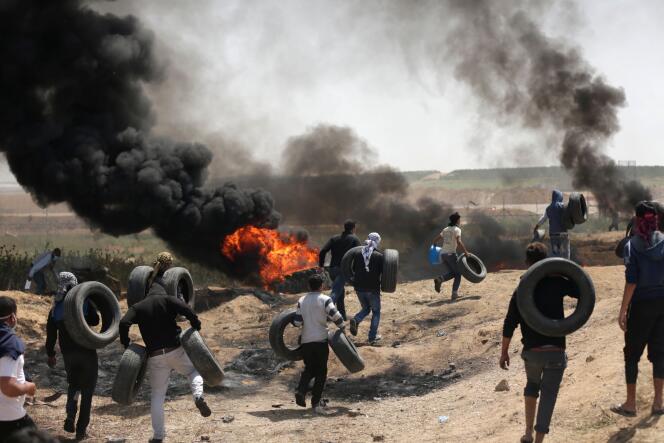 Des Palestiniens font brûler des pneus pour ne pas être vus distinctement par les tireurs israéliens, à la frontière entre la bande de Gaza et Israël, le 6 avril.