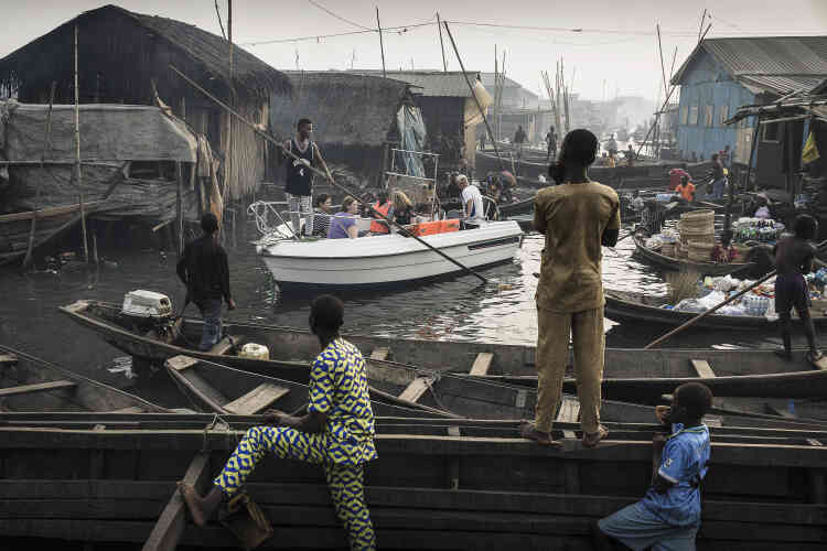 Un bateau de touristes conduit à travers les canaux de la communauté Makoko, un ancien village de pêcheurs développé en une énorme colonie informelle, sur les rives du lagon de Lagos au Nigéria, le 24 février 2017.
