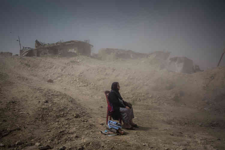 Après la reprise de l’ouest de Mossoul, en Irak, Nadhira Aziz, assise à quelques mètres de sa maison détruite dans un bombardement, attend qu’on extraie les restes des corps de sa soeur et de sa nièce des décombres.