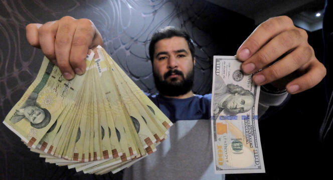 Dans un bureau de change de Téhéran en janvier 2016, un employé pose avec un billet de 100 dollars et l’équivalent en rials.