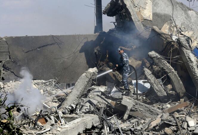 Un soldat syrien éteint les flammes dans les décombres du Centre d’études et de recherches scientifiques (SSRC), à Damas, le 14 avril.