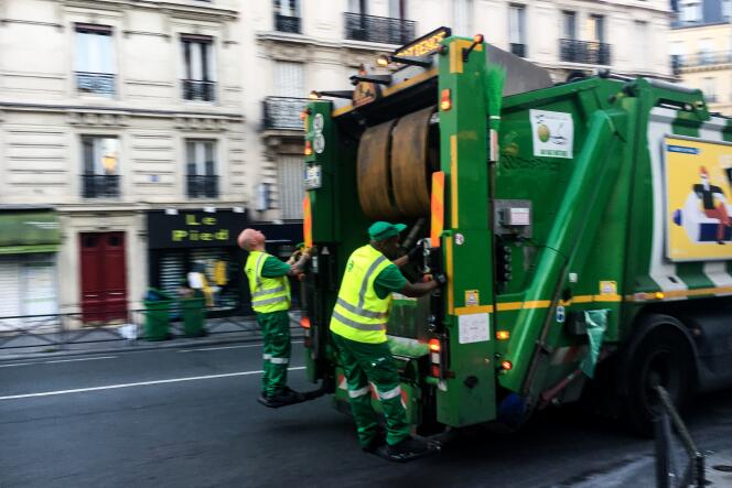 Frédéric et Yoan, sur le marchepied à l’arrière de la benne à ordures, lors d’une collecte de déchets, le 18 avril, à Paris.