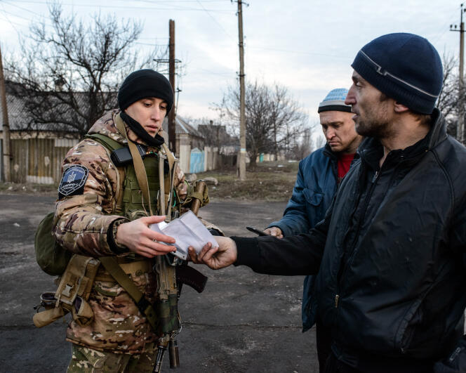 Un membre du régiment de police Dnipro 1 contrôle les passants durant une patrouille dans la rue Lénine, à Marinka (Ukraine), le 22 février.