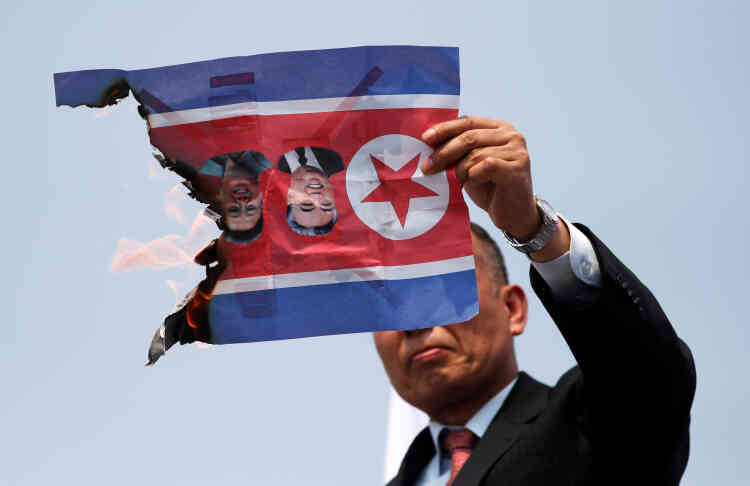 Un homme brûle un drapeau nord-coréen incrusté des photos des dirigeants nord-coréens Kim Il-sung et Kim Jong-il, alors qu’il participe à un rassemblement contre le sommet, à Paju.
