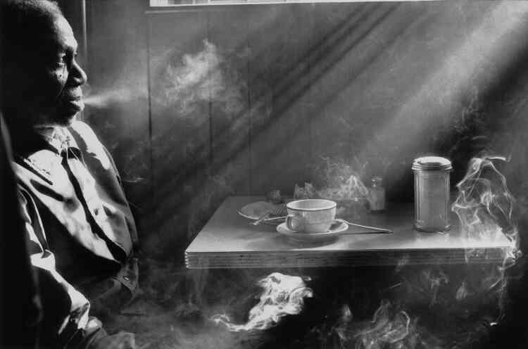 « Cette photographie a été prise dans un restaurant de la 14e rue, à Manhattan. Une scène ordinaire à une époque où café rimait avec cigarette, mais une scène magnifiée par cette lumière douce et pénétrante qu’Harold Feinstein a su capter avec brio. »