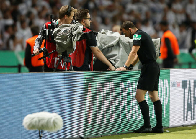 Un arbitre allemand vérifiant une action sur l’écran en bord de terrain, lors d’un match de Bundesliga.