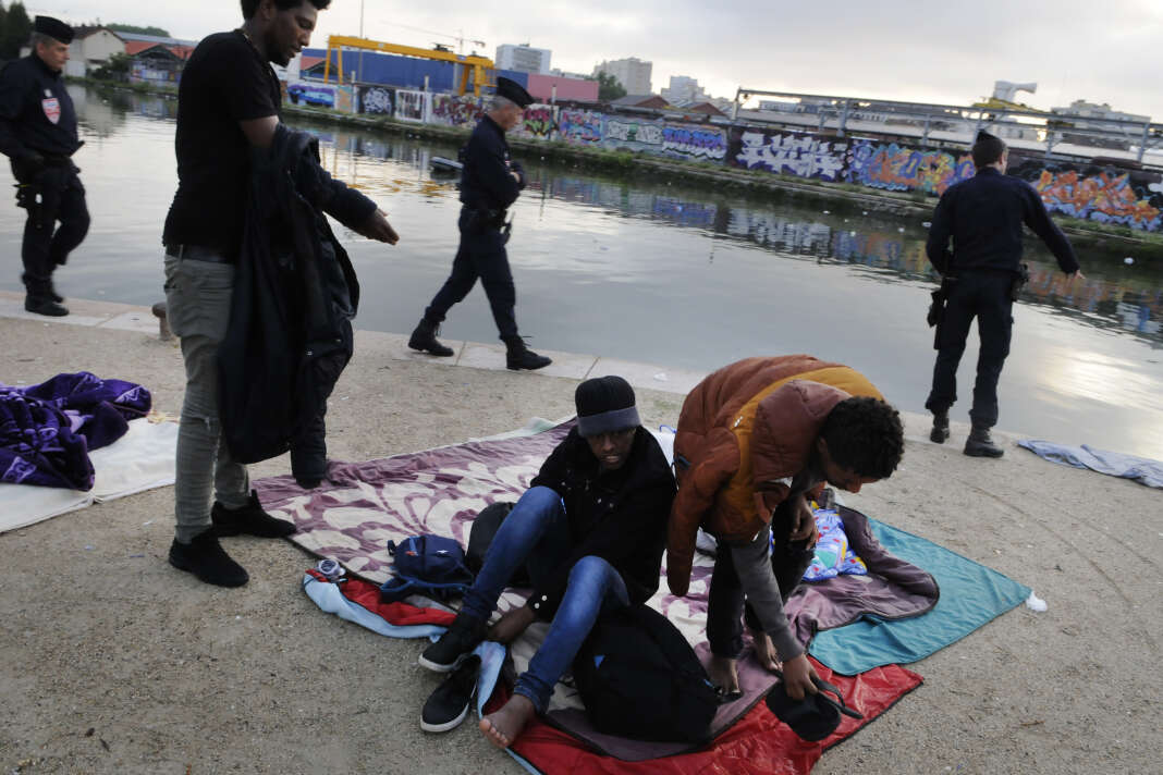 Trois migrants érythréens se préparent à être évacués, le long du canal Saint-Denis, le 30 mai.