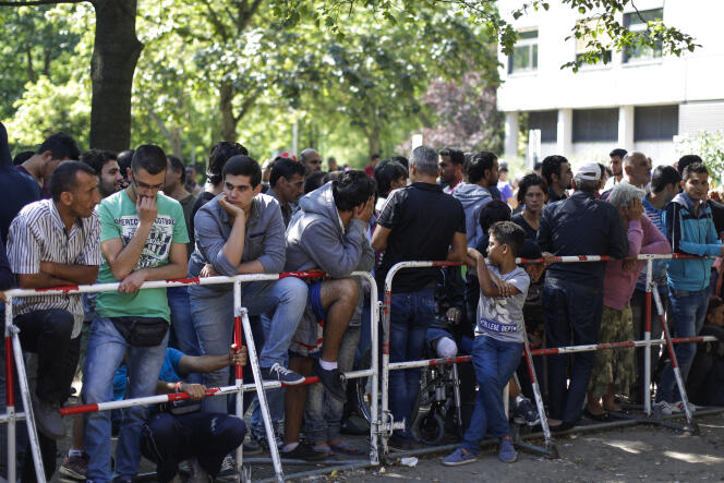 Des personnes patientent devant un centre d’accueil pour les réfugiés et demandeurs d’asile à Berlin, le 21 août 2015.
