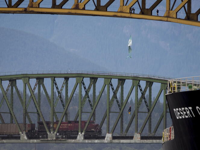 Les militants écologistes ont déroulé des câbles mardi 3 juillet au matin sous la structure d’acier du pont de Vancouver pour s’y installer et déployer de longues oriflammes, bloquant ainsi le passage des cargos.