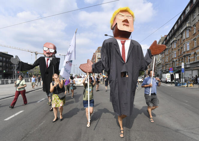 Des manifestants agitent des marionnettes représentant Donald Trump  et le premier ministre belge, Charles Michel, le 7 juillet, à Bruxelles.
