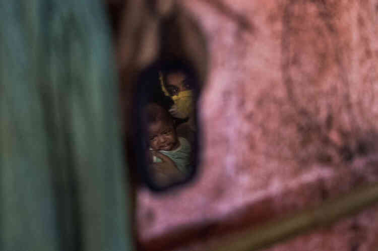 « M » est assise avec son enfant dans les bras à l’intérieur de son abri au camp de réfugiés de Kutupalong, au Bangladesh.