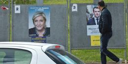 A man looks at campaign posters showing faces of far-right presidential candidate Marine Le Pen, left, and Independent centrist presidential candidate Emmanuel Macron in Saint-Cyr-L'École, France, west of Paris, Thursday, April 27, 2017. The May 7 runoff of the French presidential election will be between the populist Marine Le Pen and centrist Emmanuel Macron. (AP Photo/Michel Euler)