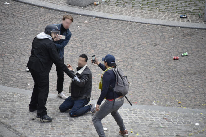 Alexandre Benalla maintient à terre le jeune manifestant place de la Contrescarpe à Paris, tandis qu'un homme filme la scène le 1er mai dernier.