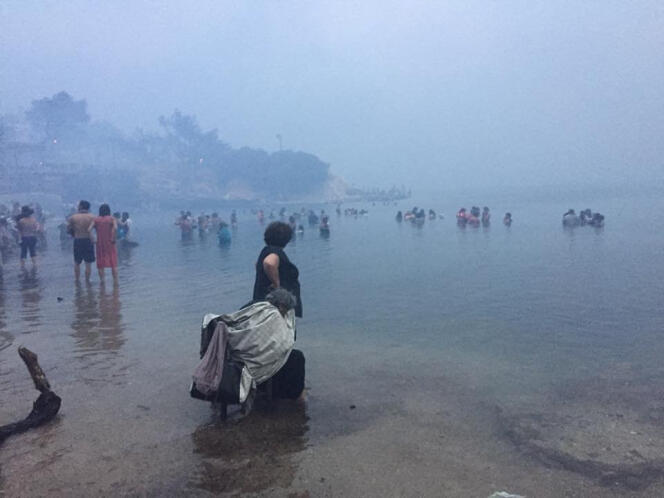 Les habitants se réfugient dans la mer alors que la fumée continue d’envahir le village de Mati, près d’Athènes, le 24 juillet.