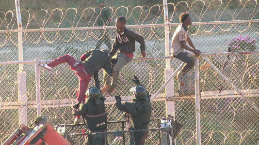 Des migrants en train d’escalader la clôture de la frontière de Ceuta, jeudi 26 juillet.