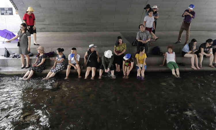 Des visiteurs se reposent à l’ombre dans le courant du Cheonggyecheon, dans le centre-ville de Séoul, en Corée du Sud, le 23 juillet. La vague de chaleur qui s’est emparée d’une large partie du Japon a également atteint la Corée du Sud voisine.