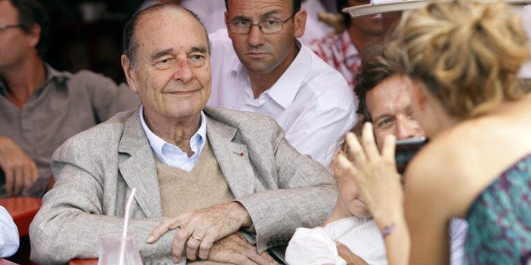 France's former president Jacques Chirac poses as a womans takes a picture of him sitting at a table outside the famous Le Senequier café in the French Riviera searesort of Saint-Tropez on August 14, 2011. AFP PHOTO SEBASTIEN NOGIER / AFP PHOTO / SEBASTIEN NOGIER