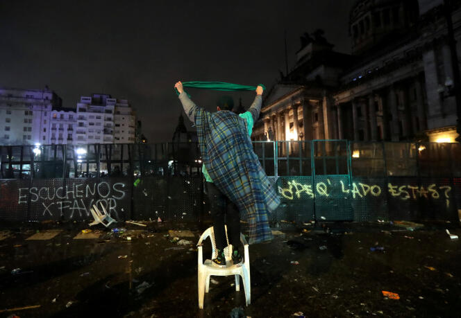 Un homme brandit un mouchoir vert, symbole des partisans du droit à l’avortement, face aux policiers devant le Congrès à Buenos Aires après le vote des sénateurs, dans la nuit du 8 au 9 août.