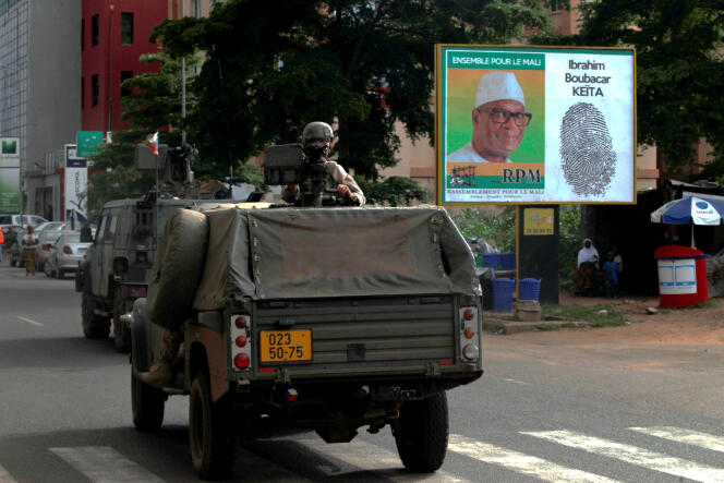 Un convoi des forces de sécurisation devant une affiche électorale du candidat Ibrahim Boubacar Keïta, à Bamako, le 9 août.