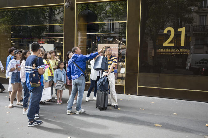 Des touristes asiatiques devant le Shopping & Welcome Center, boulevard Haussmann à Paris.