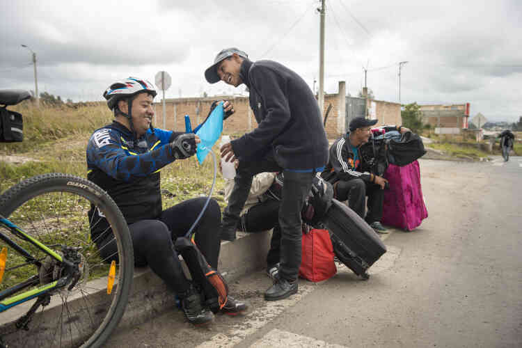 Un cycliste équatorien offre son eau à un groupe de migrants vénézuéliens.