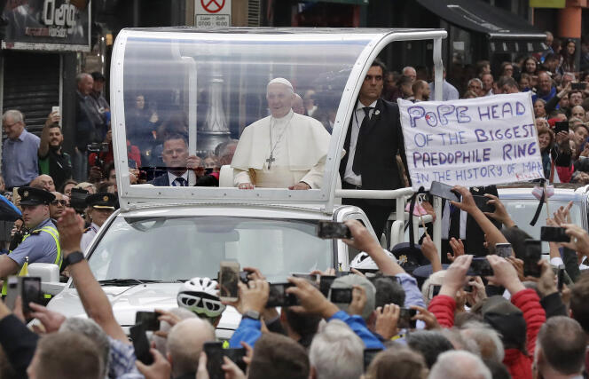 Le pape François quitte la pro-cathédrale Sainte-Marie alors qu’un manifestant brandit une banderole au message hostile, à Dublin, le 25 août.