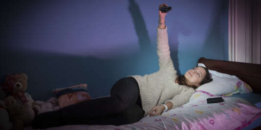 Adolescente dans sa chambre et sur son lit avec son appareil photo et ses peluches. Extrait de la  série « L’Antre de la jeunesse » (2015-2017).