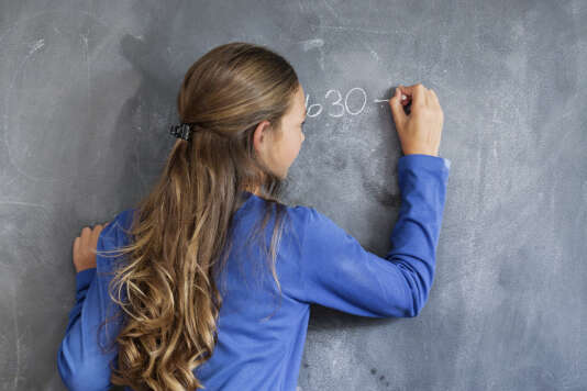 Gros plan sur une jeune fille qui écrit au tableau dans une salle de classe