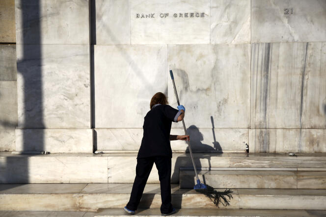 Une employée nettoie l’entrée de la Banque de Grèce, à Athènes, en juillet 2015.