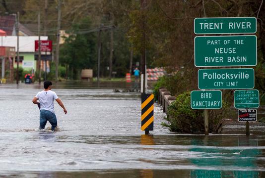 ANDREW CABALLERO-REYNOLDS / AFP Un homme tente de traverser un pont submergé à Pollocksville en Caroline du Nord, le 16 septembre.
