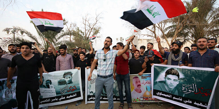 Demonstrators hold national flags and images of protesters who were killed during previous demonstrations, demanding better public services and jobs, in Basra, Iraq, Wednesday, Sept. 12, 2018. (AP Photo/Nabil al-Jurani)