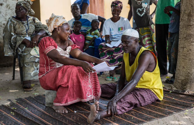 Marcelle Thiombane, « relais » de la campagne nationale de lutte contre la tuberculose, discute, en septembre 2018, avec un ancien « cas manquant » qu'elle a trouvé dans son village du département de Tivaouane, au Sénégal.