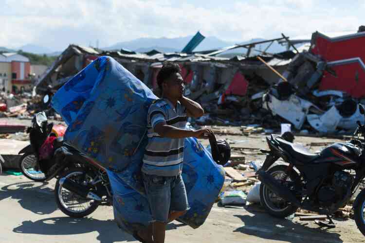 Un survivant récupère des objets utilisables dans les décombres de Palu, lundi 1er octobre. A la faveur du séisme et du chaos qui a suivi, jusqu’à 1 200 détenus se sont évadés de trois prisons différentes, ont annoncé, lundi, les autorités.
