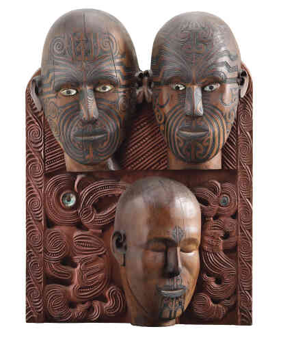 « L’un des sculpteurs maoris les plus importants et les plus novateurs de sa génération, Tene Waitere, a été chargé par Augustus Hamilton de créer cette représentation de trois personnes pour illustrer la différence entre les tatouages faciaux masculin et féminin. »