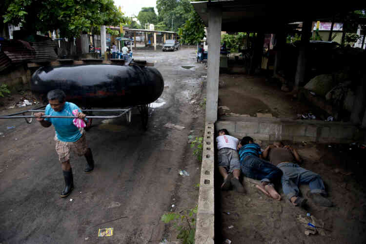 Dans la ville de Tecun Uman, à la frontière mexicaine côté Guatemala, un homme porte un radeau de fortune, tandis que des migrants honduriens dorment, le 19 octobre.