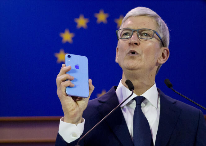 Le patron d’Apple Tim Cook brandit un iPhone, mercredi 24 octobre à Bruxelles.