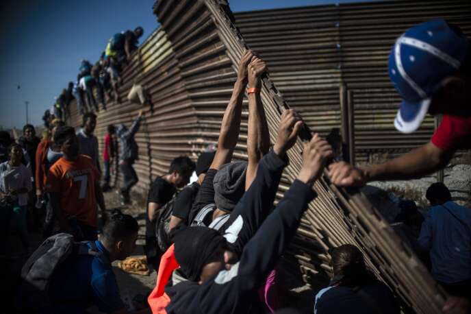 Un grupo de migrantes está tratando de cruzar la barrera de delimitación metálica entre México y Estados Unidos, en Tijuana, el 25 de noviembre.
