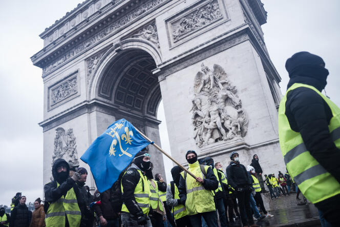 Au pied de l’Arc de triomphe, des manifestants arborent un drapeau avec le blason de Jeanne d'Arc.