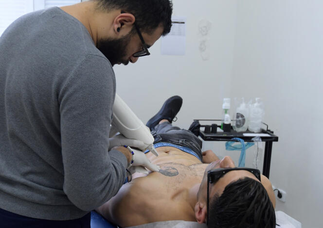 Le tatoueur Fawez Zahmoul enlève un tatouage à son client dans son école à Tunis, le 8 novembre 2018.