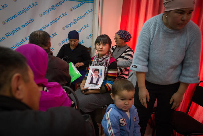 Dans les locaux de l'association Atajurt, une femme tient le portrait d'un de ses proches disparu en Chine. Almaty, Kazakhstan, décembre 2018.