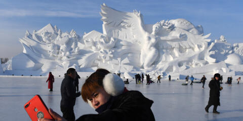 A woman takes a selfie before the opening of the annual Harbin Ice and Snow Sculpture Festival in Harbin in China's northeast Heilongjiang province on January 5, 2018. - The festival attracts hundreds of thousands of visitors annually. (Photo by Greg Baker / AFP)