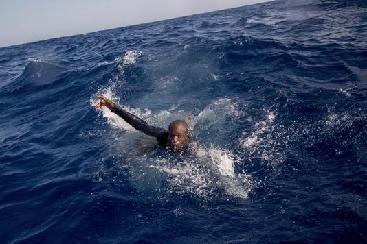 ALESSIO PADUANO / AFP Un migrant tente de monter à bord d’un canot de l’ONG allemande Sea-Watch, au large de la Libye, le 6 novembre 2017.
