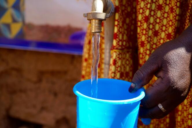 Ramata Drabo, une habitante de Tougan, dans le nord-ouest du Burkina Faso, se sert du robinet d’eau potable récemment installé à l’entrée de sa cour.