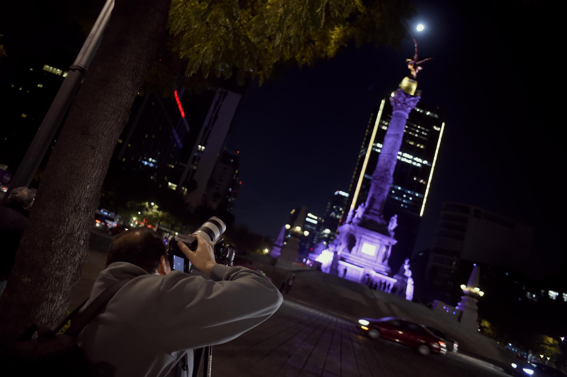 Un homme prend en photo l’éclipse devant la statue « L’Ange de l’Indépendance », à Mexico.