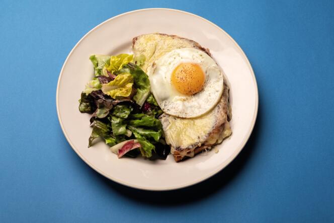 Poser le sandwich grillé sur une assiette, le couper en deux dans la diagonale, ajouter l’œuf par-dessus et servir avec une salade verte bien assaisonnée.