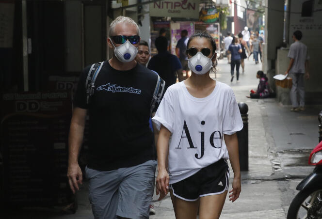 Des touristes portent des masques pour se protéger de la pollution dans une zone touristique de Bangkok, vendredi 1er février 2019.