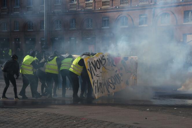 Des manifestants se protègent des gaz lacrymogènes envoyés par les forces de l’ordre derrière une banderole durant la mobilisation des « gilets jaunes » à Toulouse, le 9 février.