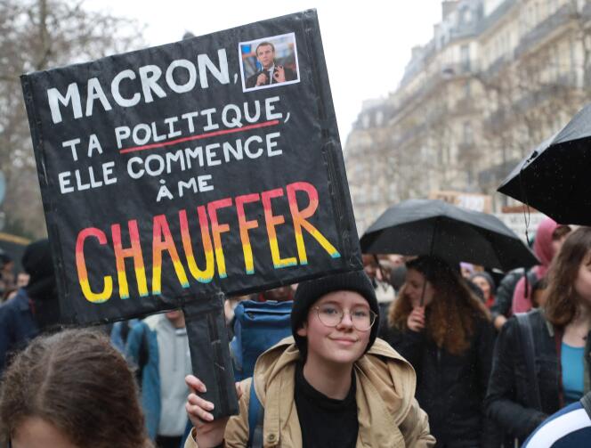 A protester holds up a sign targeting Emmanuel Macron during a protest against global warming in Paris, March 1, 2019.