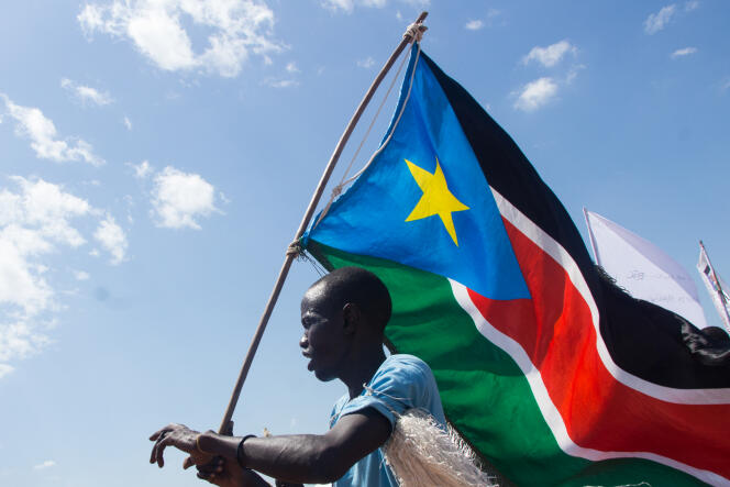 Un homme brandit le drapeau sud-soudanais dans le camp de déplacés de Mangateen, à Juba, le 17 novembre 2018.